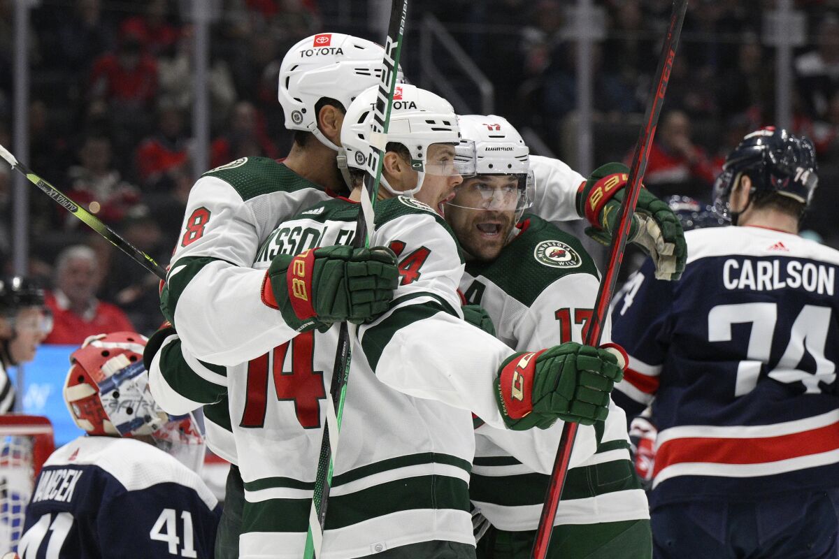Minnesota Wild center Joel Eriksson Ek (14) celebrates his goal with left wing Marcus Foligno (17) and left wing Jordan Greenway (18) during the second period of the team's NHL hockey game against the Washington Capitals, Sunday, April 3, 2022, in Washington. (AP Photo/Nick Wass)