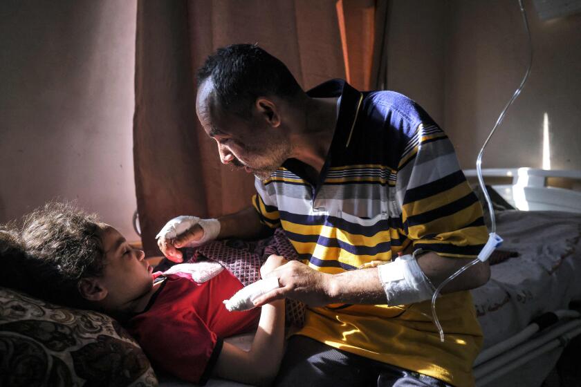 Palestinian Ryad Eshkuntana, checks his daughter Suzy, as they receive medical care at Al-Shifa hospital in Gaza City, on May 19, 2021, after his wife and other children were killed in an Israeli air strike. - Deafening air strikes and rocket fire once more shook Gaza overnight and early today amid an international diplomatic push to broker a ceasefire after more than a week of bloodshed. (Photo by MAHMUD HAMS / AFP) (Photo by MAHMUD HAMS/AFP via Getty Images)