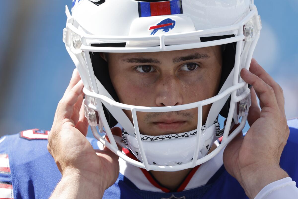 Buffalo Bills punter Matt Araiza stands on the sideline holding his helmet during a game.