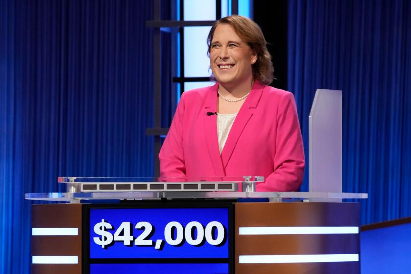 Amy Schneider wearing a pink blazer and standing behind a podium that reads "$42,000"