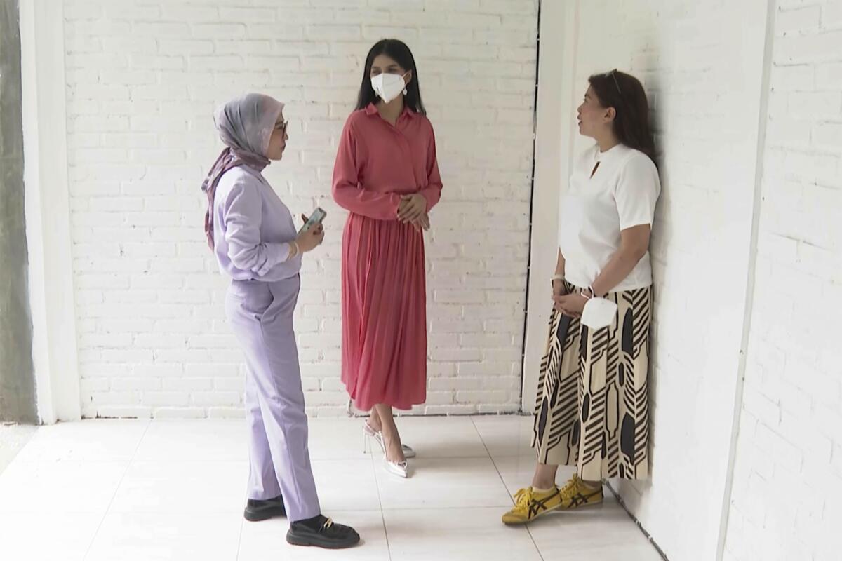 Three women talk in a hallway.