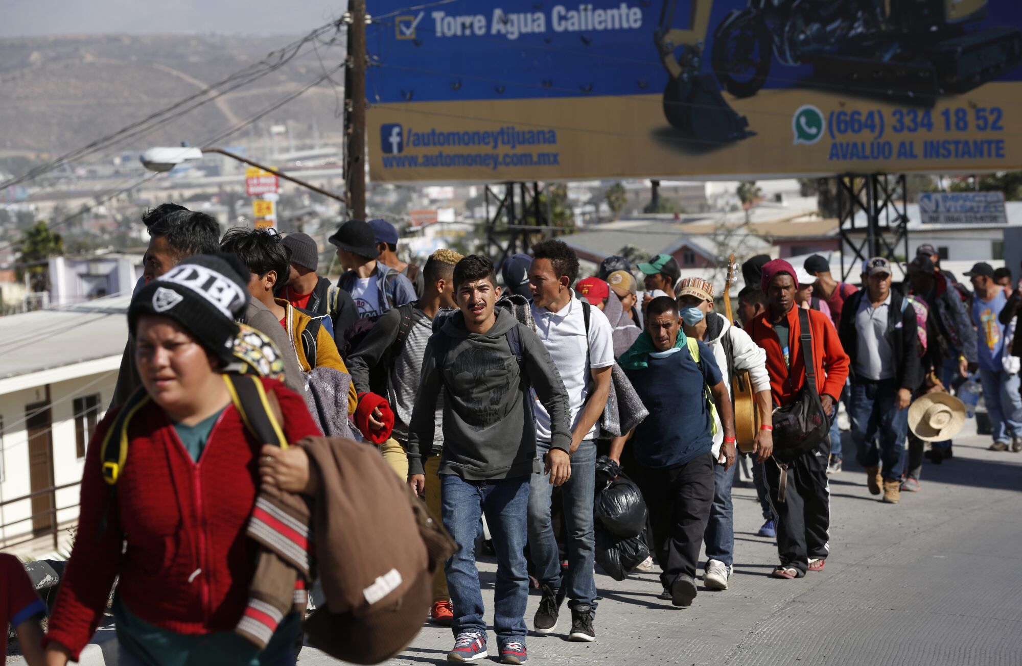 Central Americans from a migrant caravan walk along a road near the U.S. border fence in Tijuana.