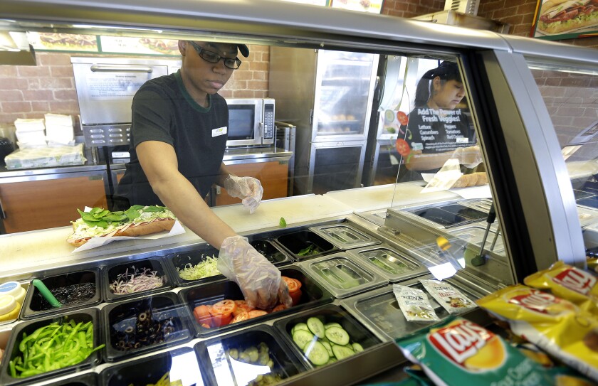 Workers make sandwiches at a Subway sandwich franchise in Seattle.