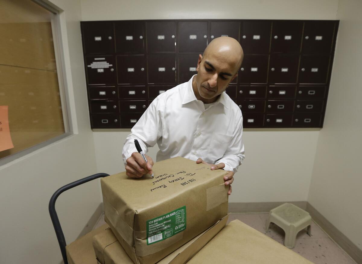 Republican gubernatorial candidate Neel Kashkari writes a note to Gov. Jerry Brown on one of the bundles of paper bags he delivered to the governor's mail room Wednesday.
