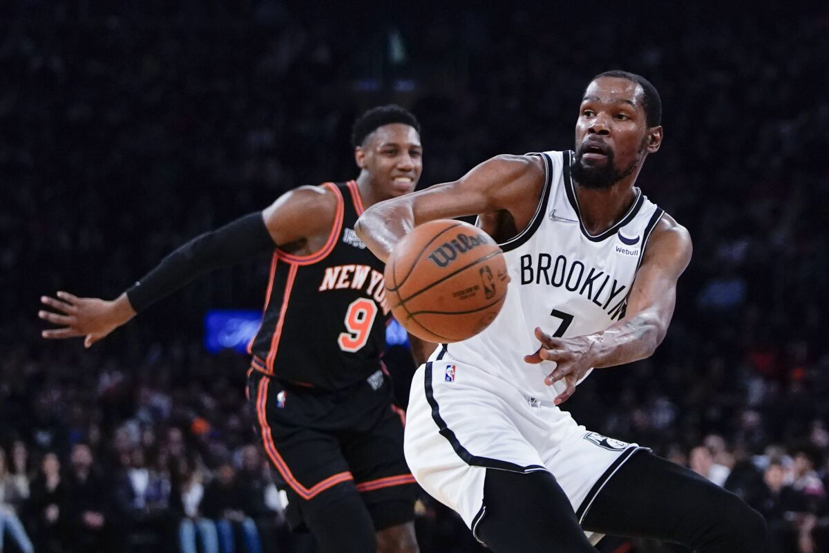 Brooklyn Nets' Kevin Durant (7) passes the ball away from New York Knicks' RJ Barrett (9) during the first half of an NBA basketball game Wednesday, April 6, 2022, in New York. (AP Photo/Frank Franklin II)