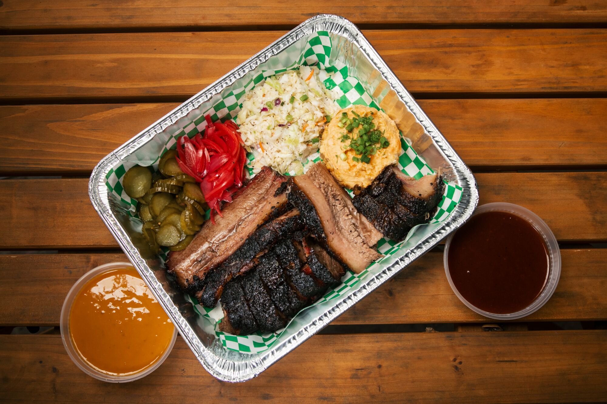 A tray with brisket, side dishes and containers of sauce.