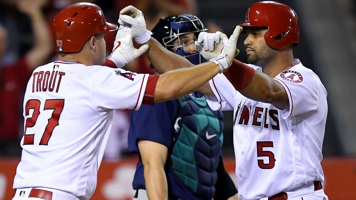 Angels designated hitter Albert Pujols is congratulated by teammate Mike Trout after hitting a three-run home run against the Mariners.