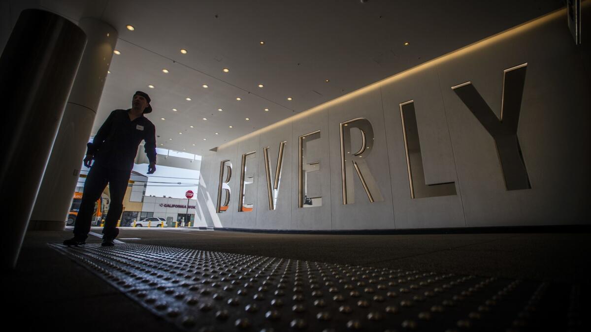 A man walks in near a large sign at the valet entrance to The Beverly Center.