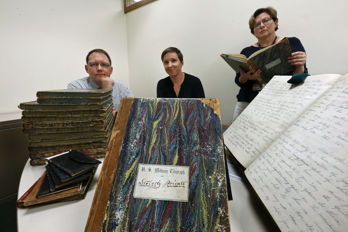Digital project librarian Mario M. Einaudi, left, library assistant Kate Peck and curator Olga Tsapina photographed with the ledgers containing Civil War telegrams from Abraham Lincoln, his Cabinet and members of the Union Army.