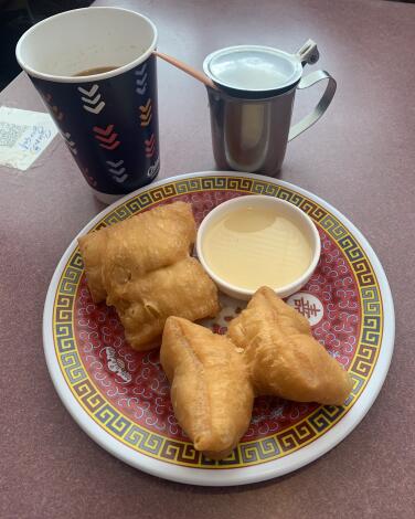 Three Chinese doughnuts on a plate with dipping sauce and coffee.