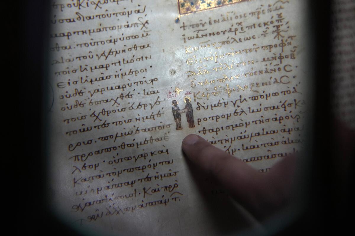 El padre Theofilos, un monje ortodoxo griego, muestra un manuscrito en la biblioteca del Monasterio 