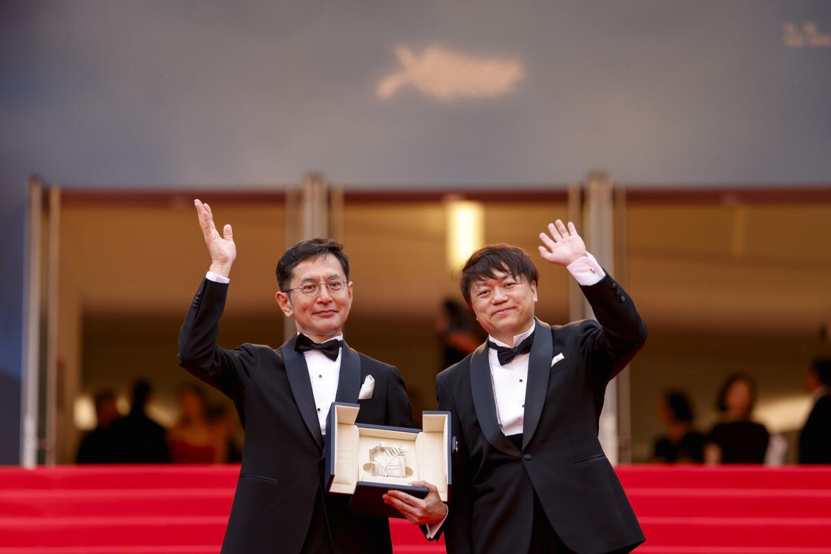 Goro Miyazaki, izquierda, y Kenichi Yoda posan para retratos con la palma de oro honoraria para el Studio Ghibli