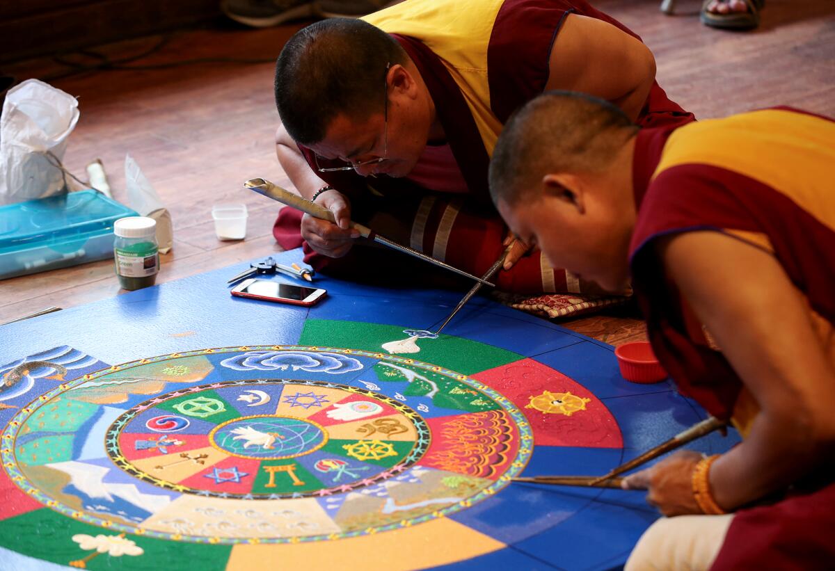Drepung Gomang monks use chak-pur tools to place sand for a colorful world peace mandala at the Sawdust Festival.