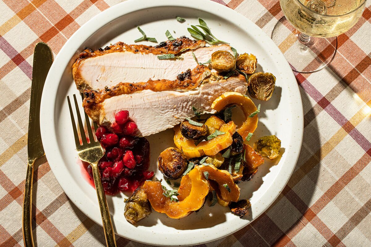 A plate with a small amount of turkey, cranberries and squash.