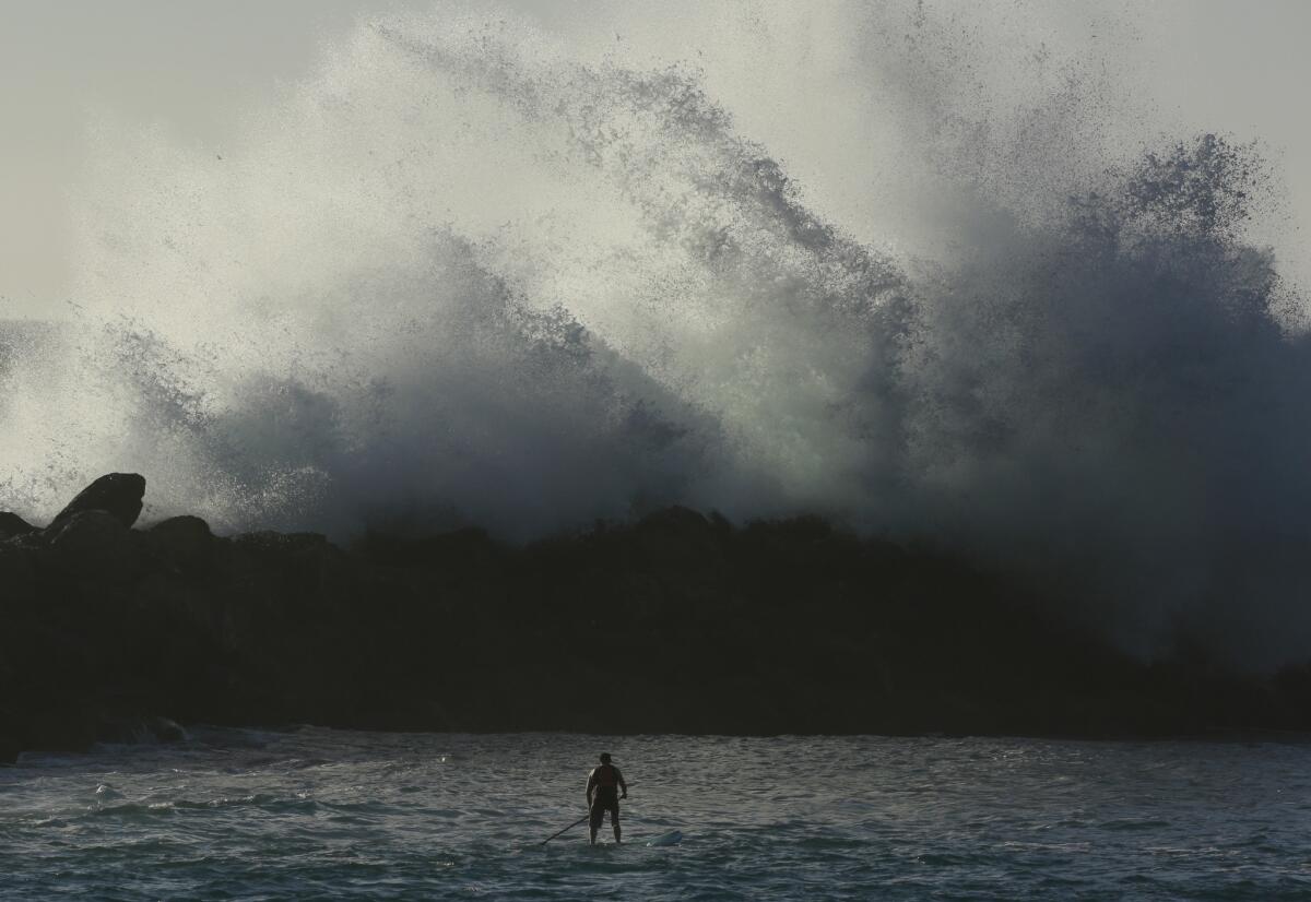 A paddle boarder gets a close view of the waves crashing against the jetty in Redondo Beach on Feb. 9.