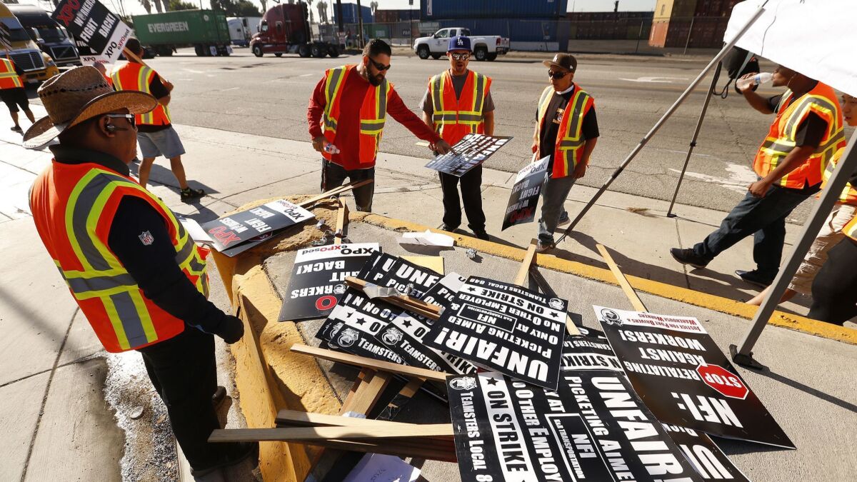 Workers select picket signs at the Intermodal Container Transfer Facility in Wilmington on Monday.