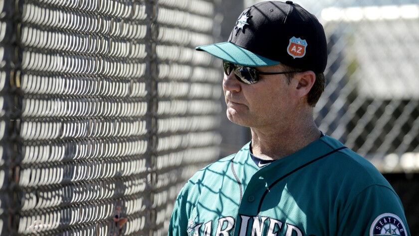 Mariners Nanager Scott Servais talks to a fan through a fence during a spring training workout.