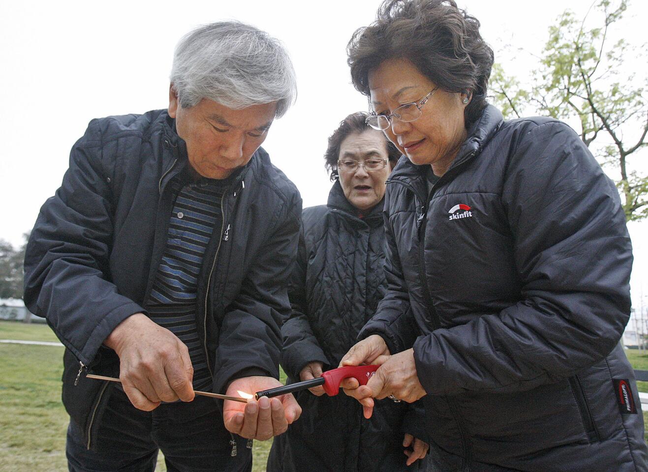Kuk Jo and Jong Jo, of Long Beach and behind the Soo Kim, of Los Angeles, light incense Hwang Keum-ja, one of 55 remaining comfort women survivors who died on Jan 25 in Korea, at the Comfort Women Statue in Central Park in Glendale on Thursday, January 30, 2014. (Tim Berger/Staff Photographer)