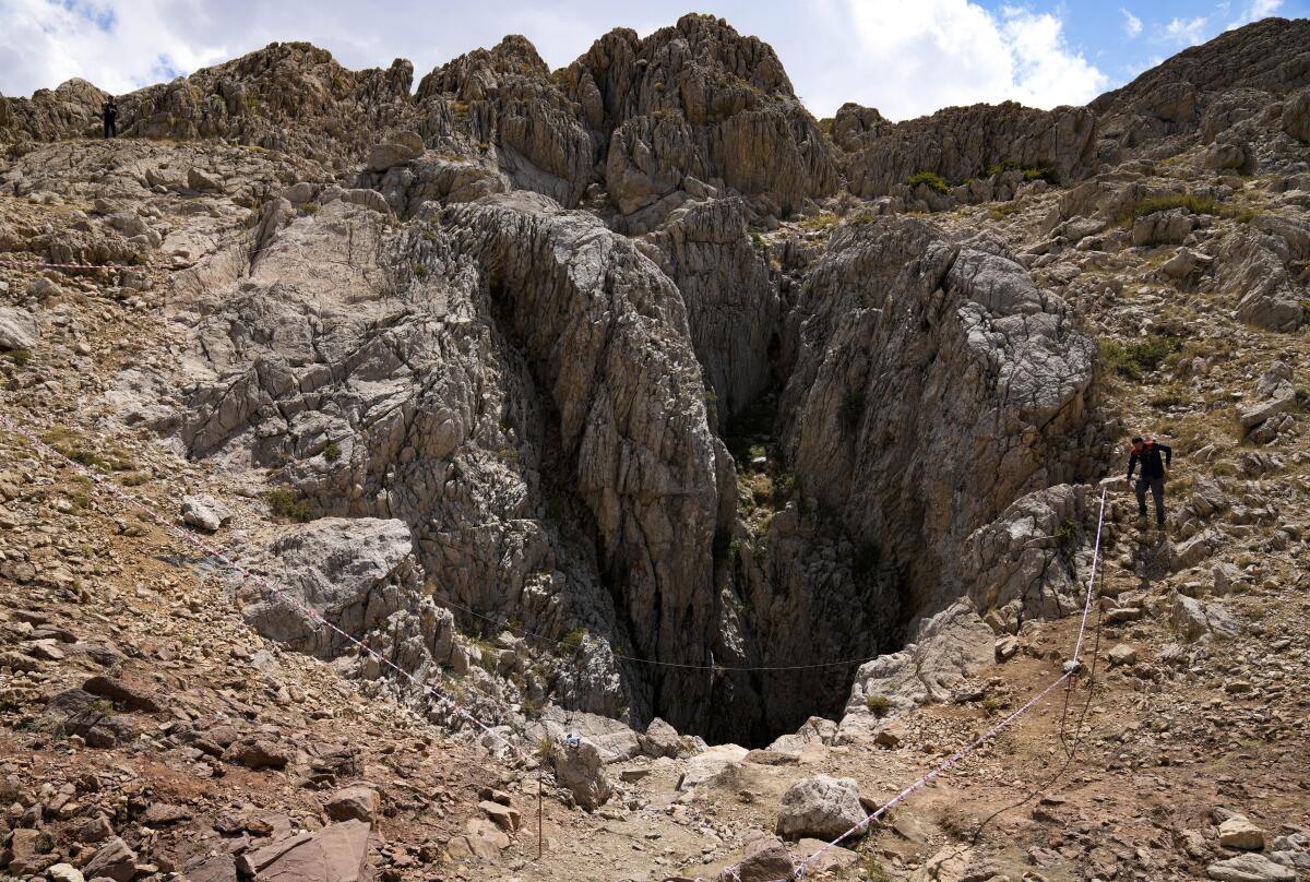 A Turkish officer walks next to a massive cave opening. 