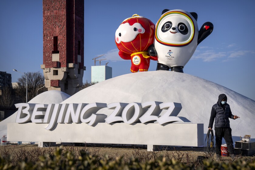 En foto de miércoles 12 de enero del 2022, un empleado camina frente a las mascotas de los Juegos Olímpicos.