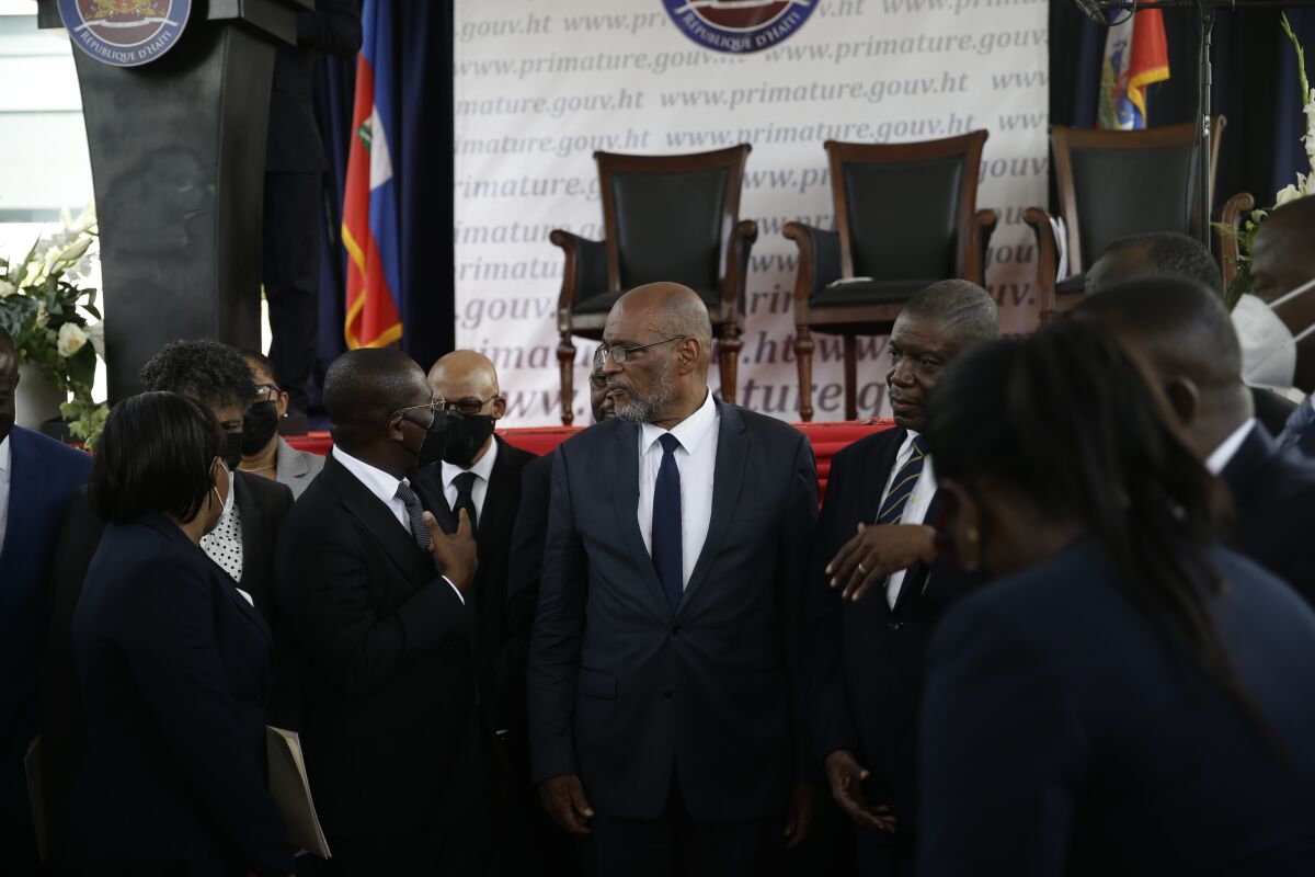 FILE - In this July 20, 2021 file photo, Prime Minister Ariel Henry, center, talks with former interim Prime Minister Claude Joseph as they stand surrounded by Henry's cabinet after his appointment in Port-au-Prince, Haiti, weeks after the assassination of President Jovenel Moise at his home. Henry faces increased scrutiny from authorities investigating Moise´s slaying. (AP Photo/Joseph Odelyn, File)
