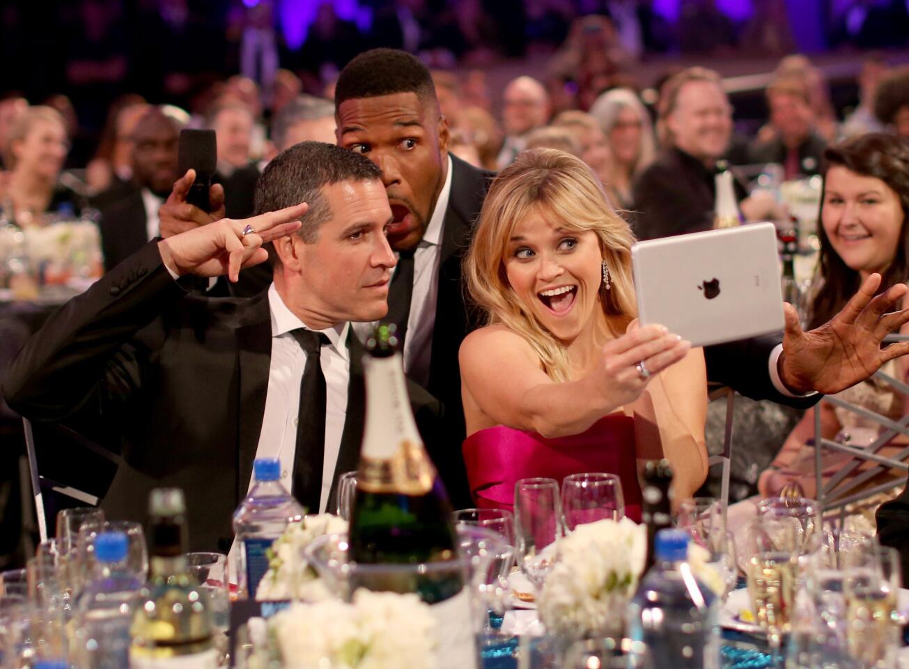 Actress Reese Witherspoon, with husband Jim Toth, left, and host Michael Strahan pose for selfies.