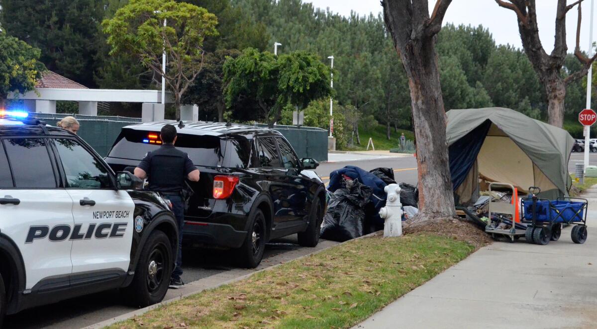 Newport Beach police clear belongings from a homeless encampment Thursday on Avocado Avenue.