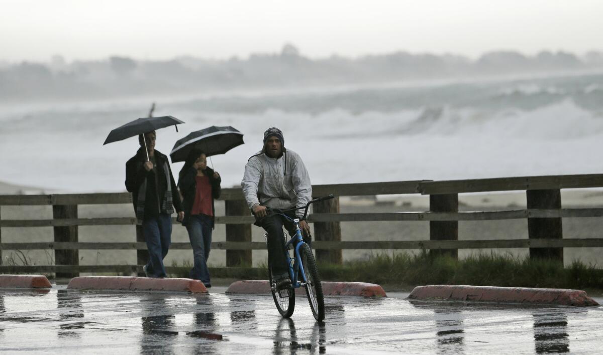 Visitors shield themselves from the rain at Seacliff State Beach on Monterey Bay on Friday.