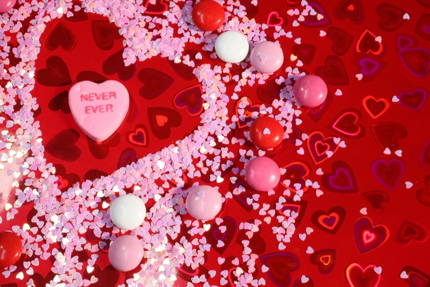 XXXL Photo. Humorous Anti Valentine with a candy that says 'never ever' with holographic red heart paper background, pink heart glitter and candy.