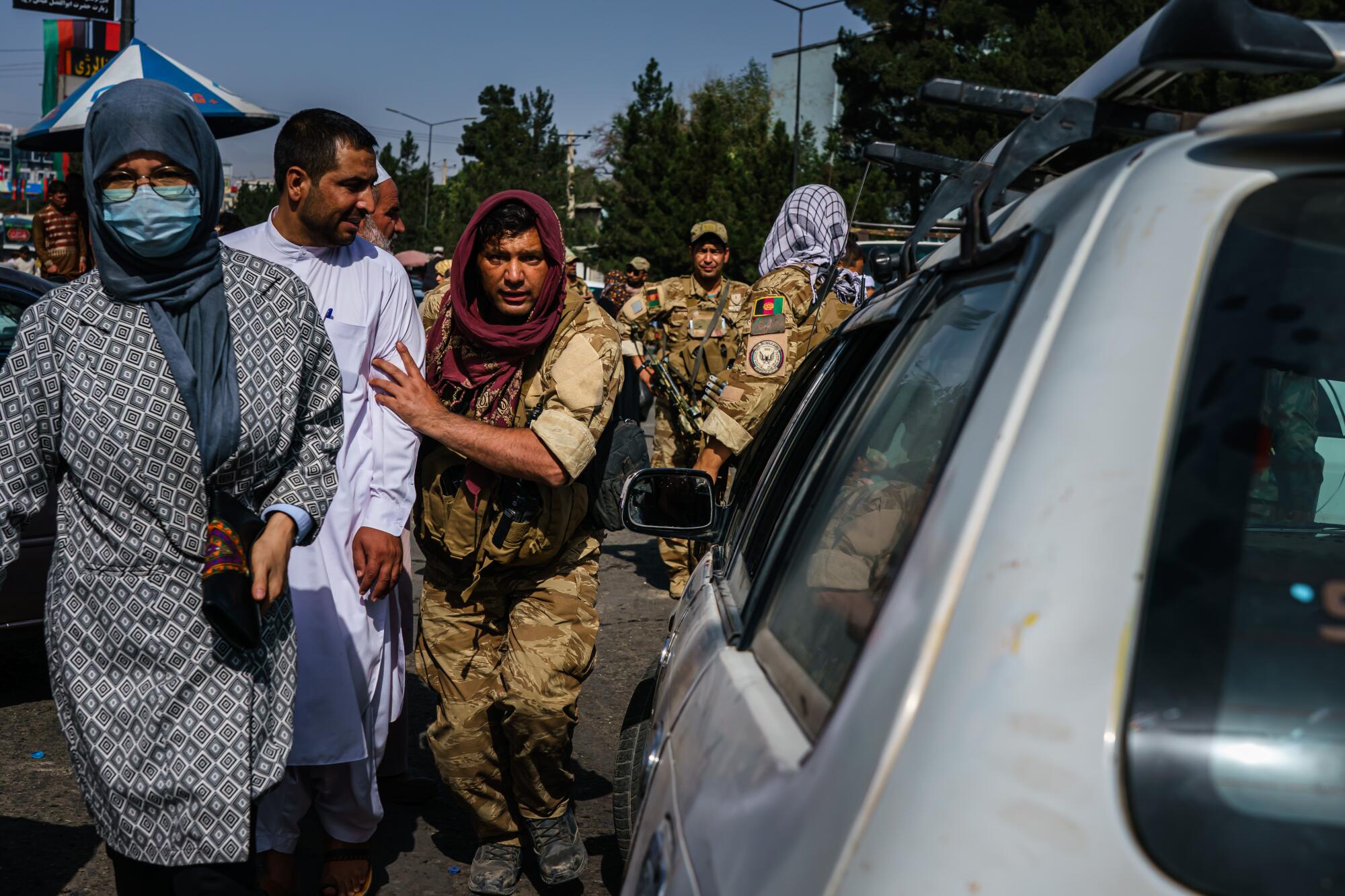 Soldiers try to guide cars and pedestrians in the street. 