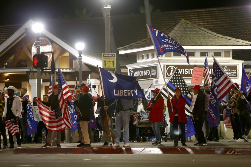 Pro-Trump protesters gathered in front of the Huntington Beach pier Saturday night to protest a nearly statewide nighttime curfew aimed at slowing the spread of COVID-19.