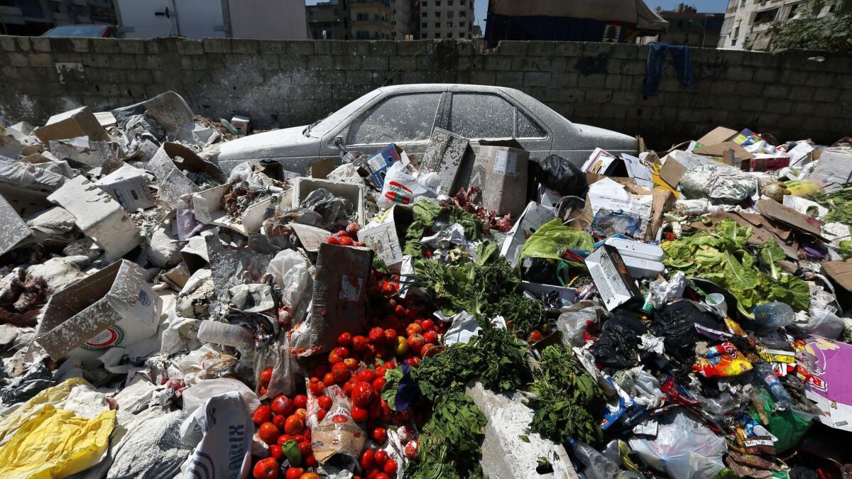 A car covered with white pesticide sits among piles of trash in the Palestinian refugee camp of Sabra in Beirut.