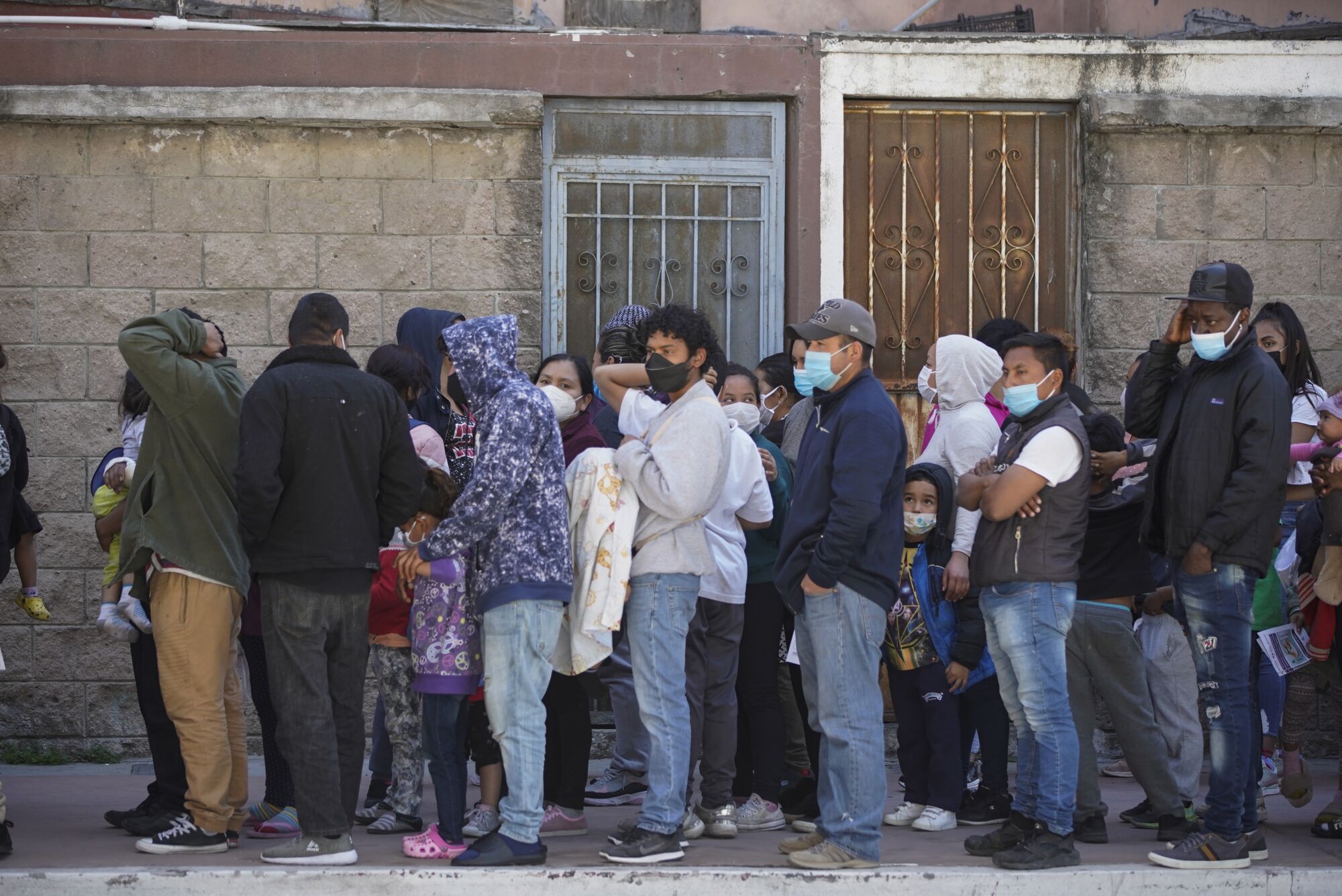 Asylum seekers wearing protective masks line up for food.