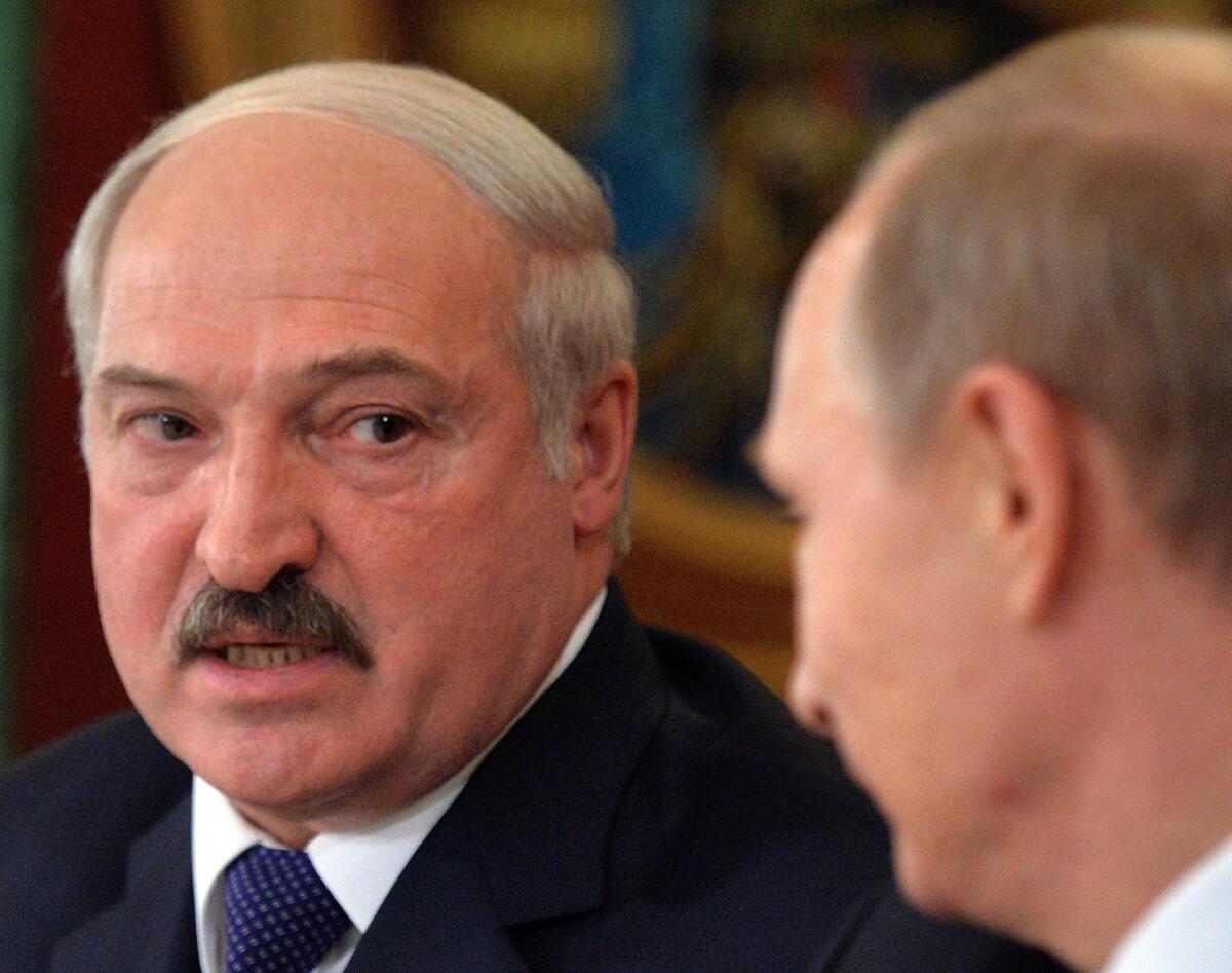 Belarus President Alexander Lukashenko, left,  visits with Russia's Vladimir Putin.