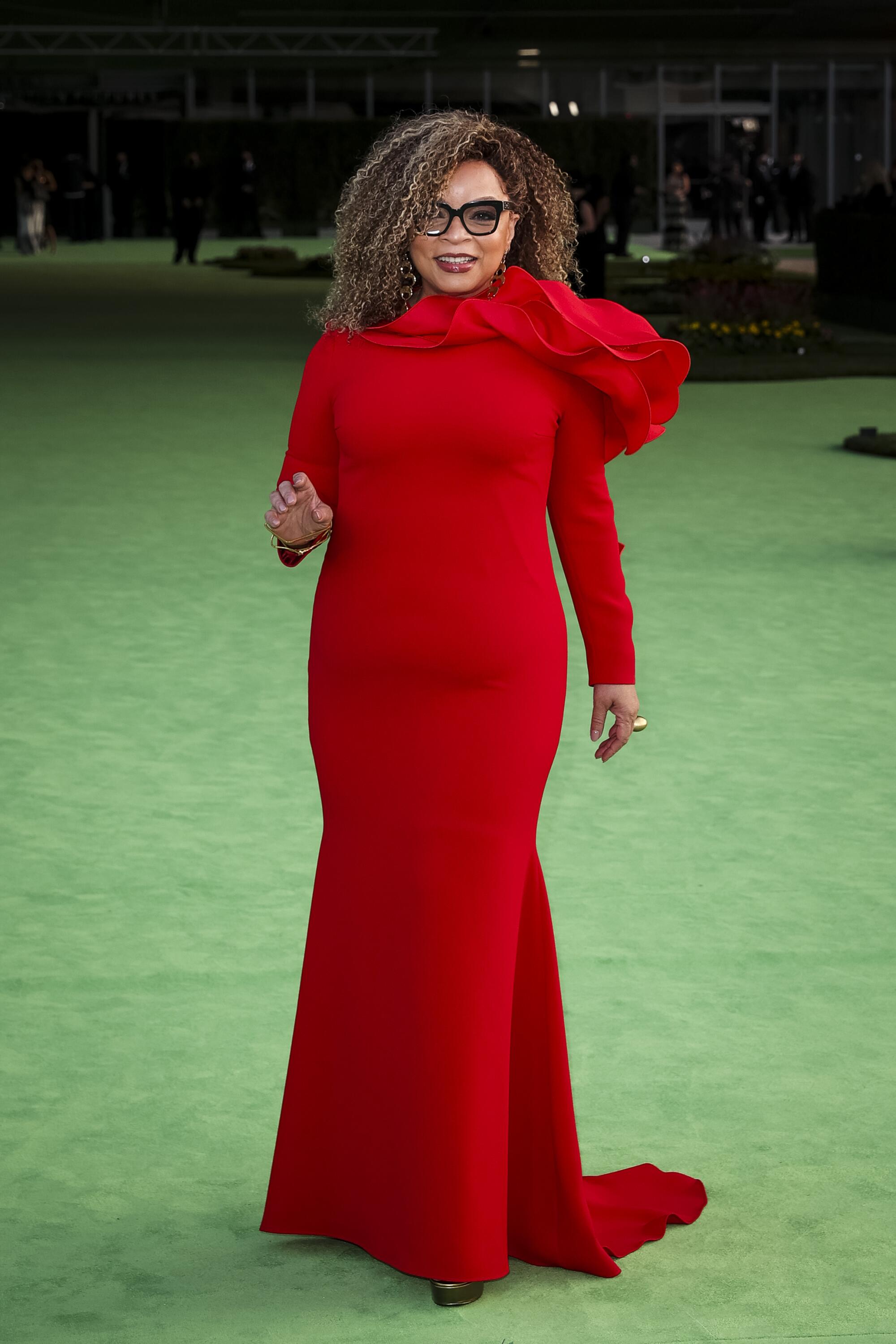 A woman in a red dress posing on a green carpet