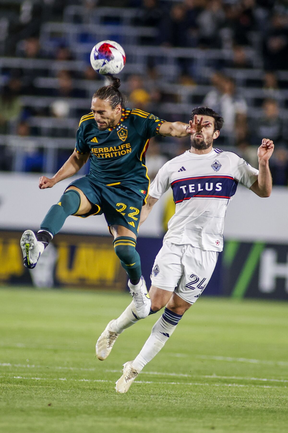 LA Galaxy defender Martín Cáceres, left, heads the ball away from Vancouver Whitecaps forward Brian White during the second half of an MLS soccer match in Carson, Calif., Saturday, March 18, 2023. (AP Photo/Ringo H.W. Chiu)