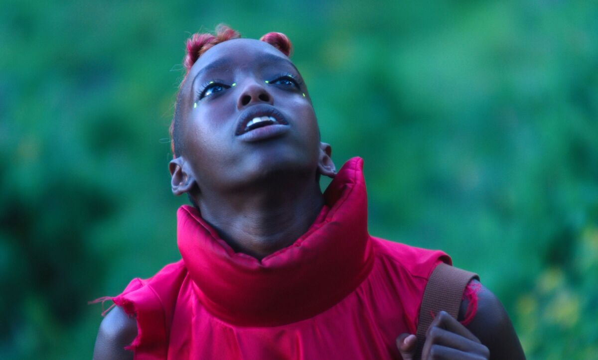 A woman in a puffy fuchsia blouse looks up.