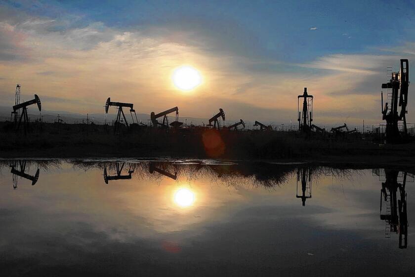 Oil pumps and equipment reflect on water pooled after a storm in Kern County in March 2014.