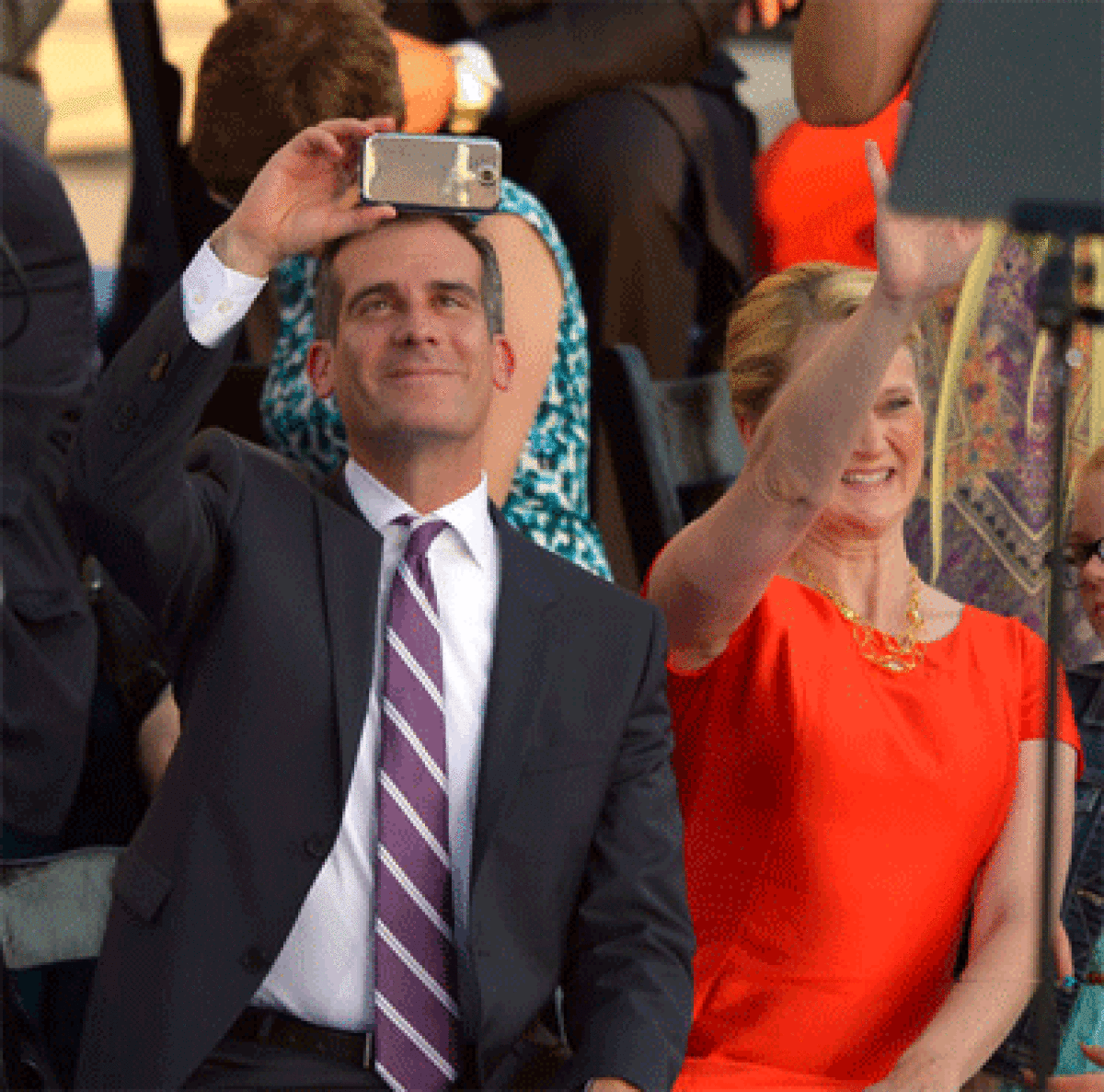 Mayor Eric Garcetti, who promises to carry Los Angeles into the "smartphone era," takes a photo of the crowd at his inauguration while his wife Amy Wakeland acknowledges supporters.