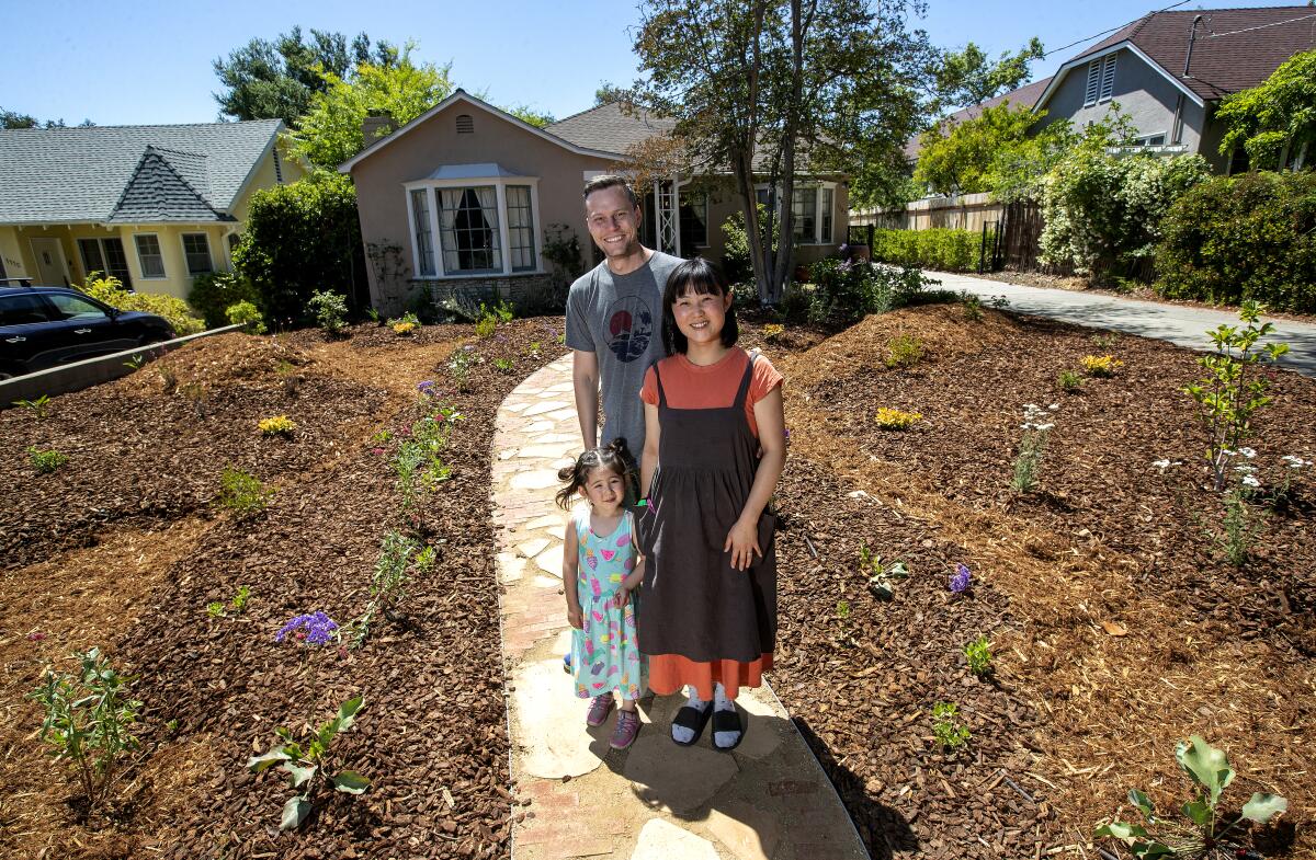A couple and their daughter in their drought-tolerant garden.