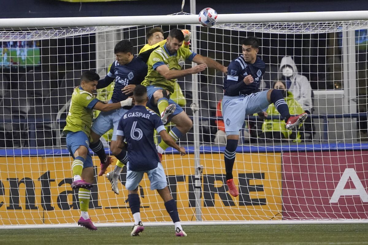 Vancouver Whitecaps goalkeeper Thomas Hasal, center rear, punches away a shot during the first half of the team's MLS soccer match against the Seattle Sounders, Saturday, Oct. 9, 2021, in Seattle. (AP Photo/Ted S. Warren)