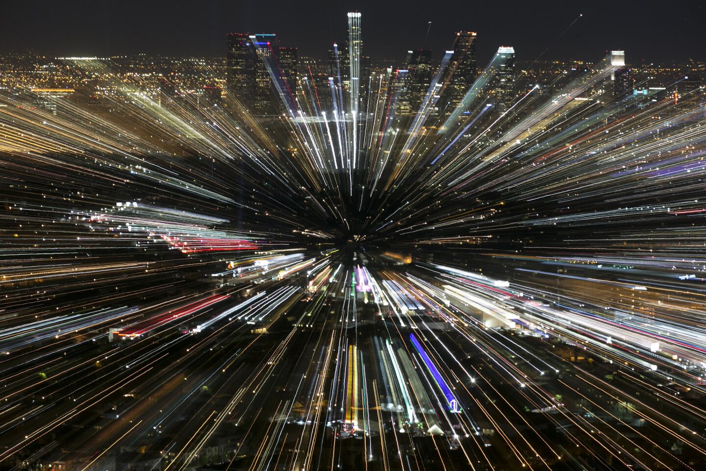 An effect created by zooming a telephoto lens during a 3 second exposure creates an explosion of light around the downtown skyline, seen from the Griffith Observatory.
