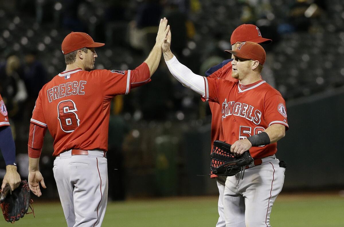 Los Angeles Angels third baseman David Freese (6) and right fielder Kole Calhoun (56) celebrate after the Angels beat the Oakland Athletics in a baseball game in Oakland, Calif., Tuesday, Sept. 1, 2015. The Angels won 6-2. (AP Photo/Jeff Chiu)