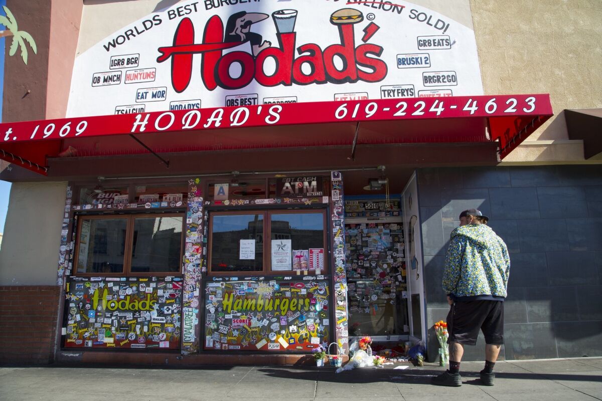 Casey Spidle made a stop at Hodad's burger restaurant to pay respect for Mike Hardin. Mourners gathered Friday and left flowers and small items at a memorial in front of the Ocean Beach eatery. — Nelvin C. Cepeda