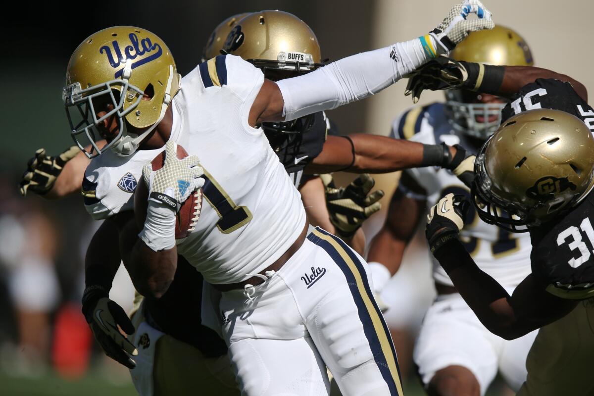 UCLA's Ishmael Adams, left, returns a punt during the first quarter of Saturday's game against Colorado.