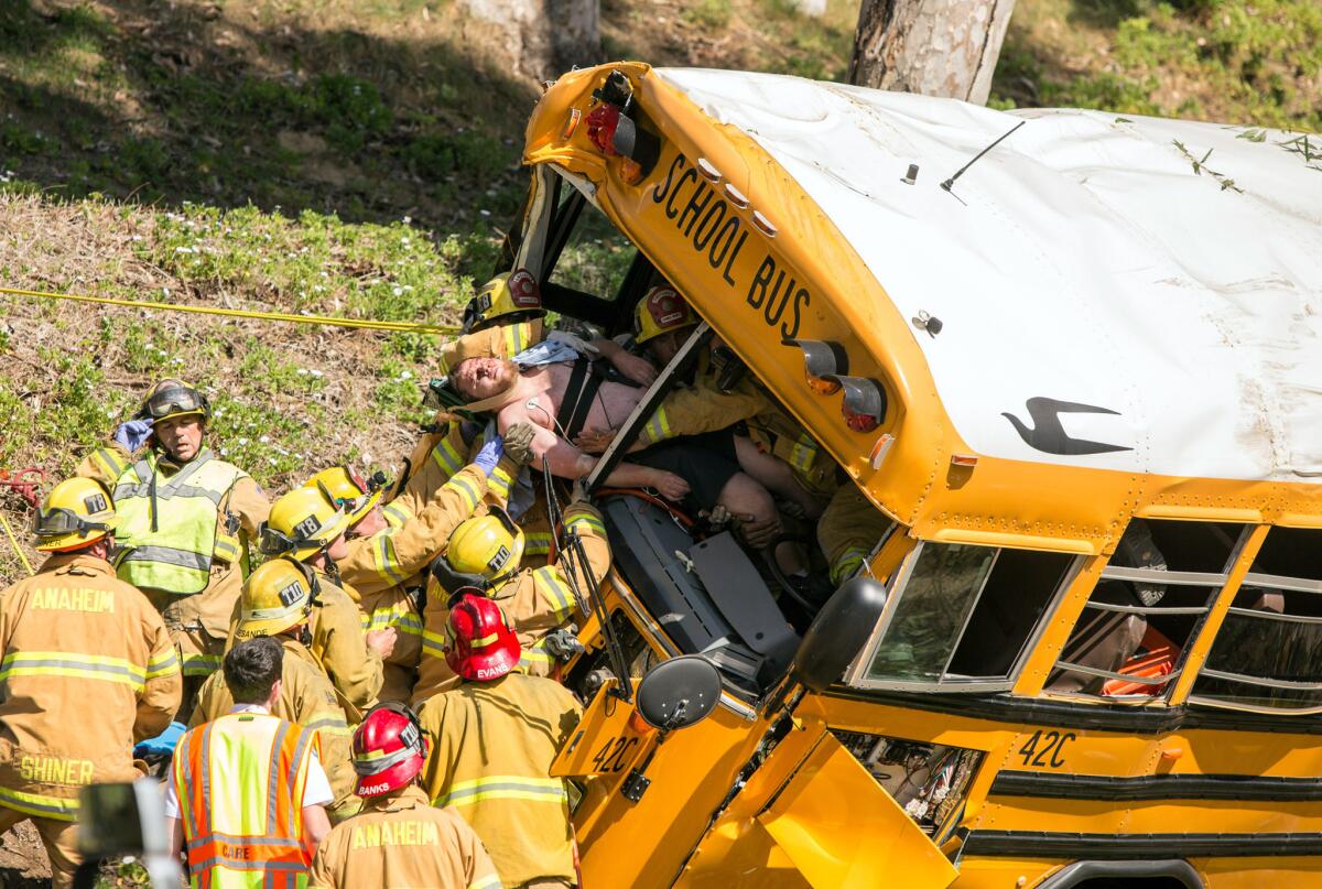 Firefighters pull the driver from the front of a school bus that crashed Thursday in the Anaheim Hills, leaving six people injured, officials say.