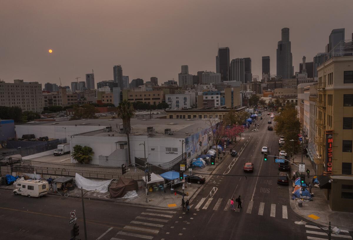 Smoke blankets the sky over a homeless encampment in skid row.