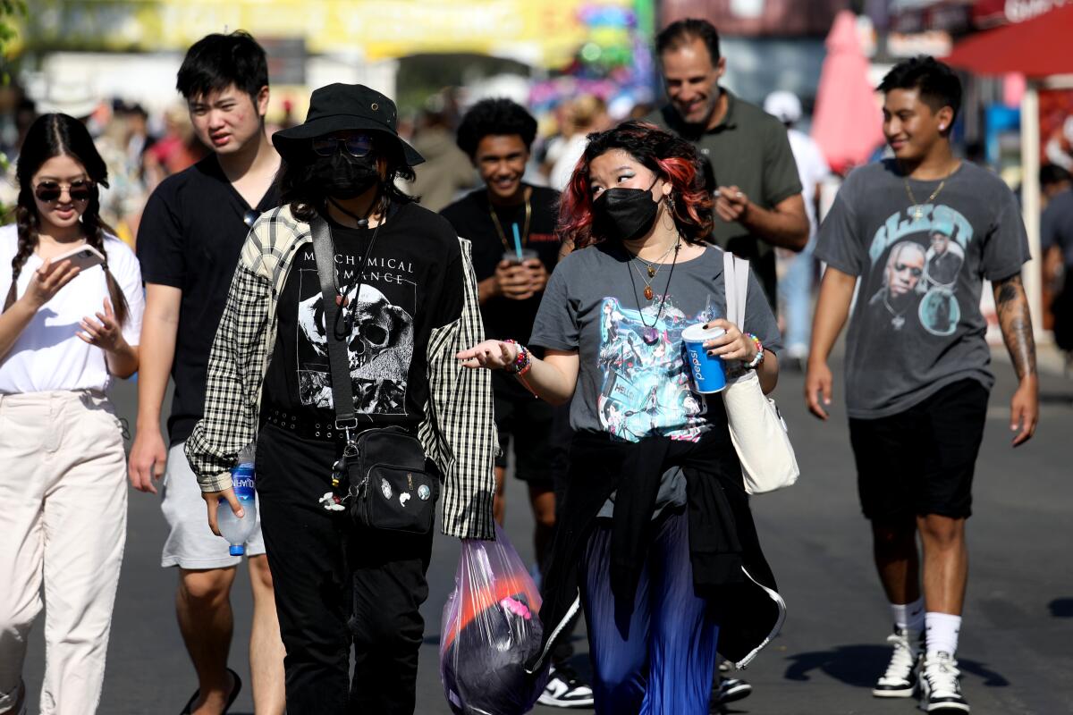 A  group of people in a crowd, some masked and some unmasked 