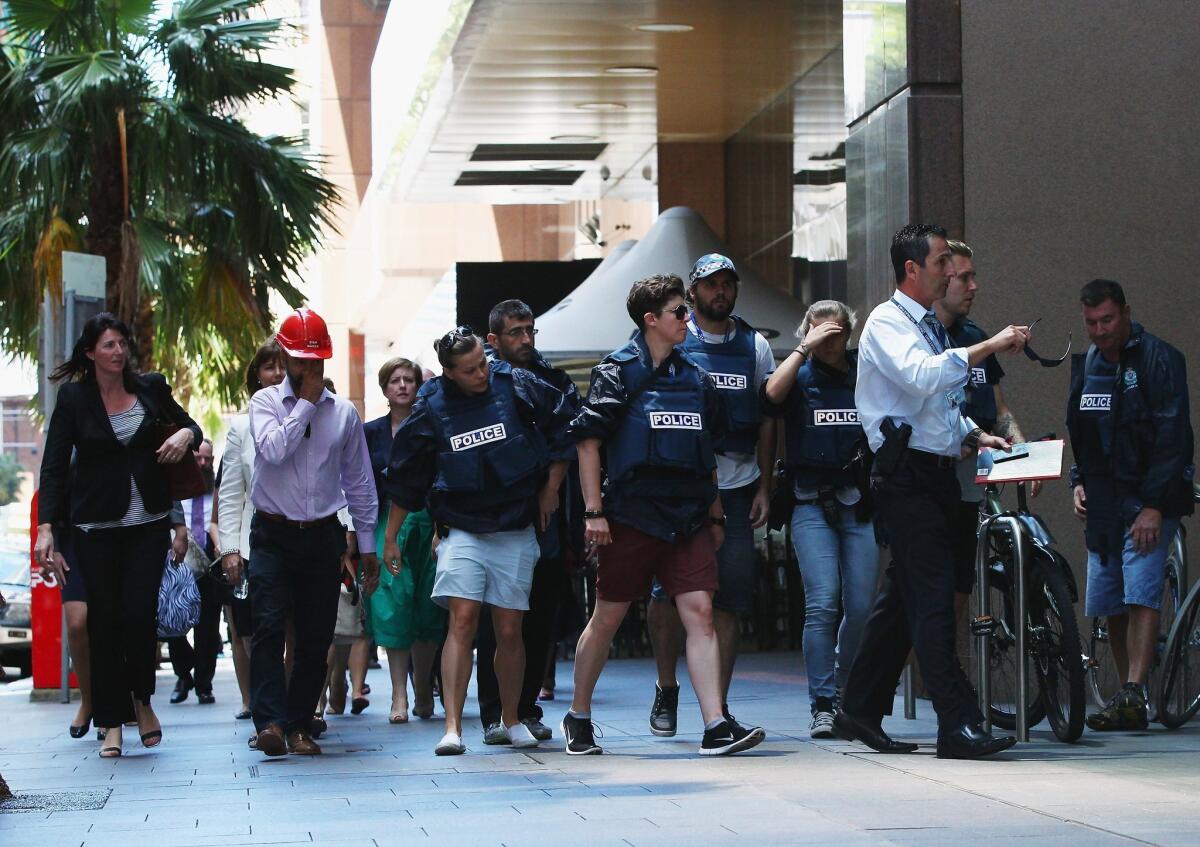 Police direct people who had been evacuated from surrounding buildings to areas outside the exclusion zone during a hostage-taking in Sydney.