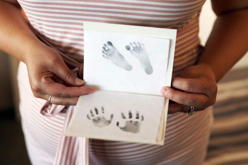 Los Angeles, CA - August 02: Christina is a California patient who had to leave the state to get an abortion in the third trimester after a poor fetal diagnosis and poses for a portrait holding foot and hand prints of her baby on Tuesday, Aug. 2, 2022 in Los Angeles, CA. Despite Democrats hailing the state as a "haven" for abortion access, patients who need abortion after viability has been reached often have to leave the state for care. (Dania Maxwell / Los Angeles Times)